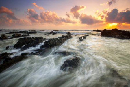 Pink Cloudy Sunset Over Rocky Ocean photo