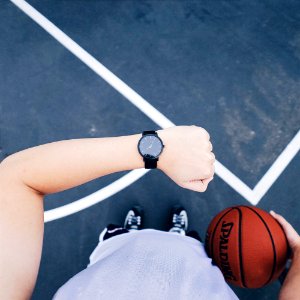 Person Wearing Black Round Analog Watch On Left Wrist While Holding Basketball On Right Hand photo