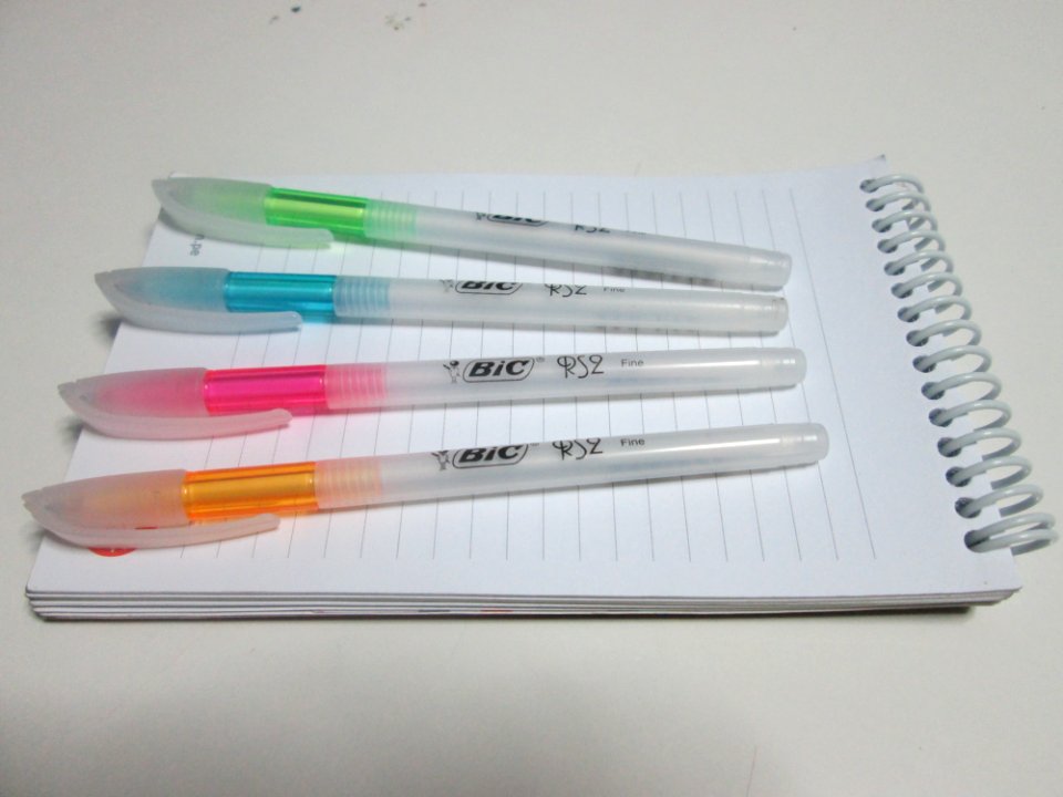 Bic Orange And White Ball Point Pens On Top Of Lined Paper Notebook