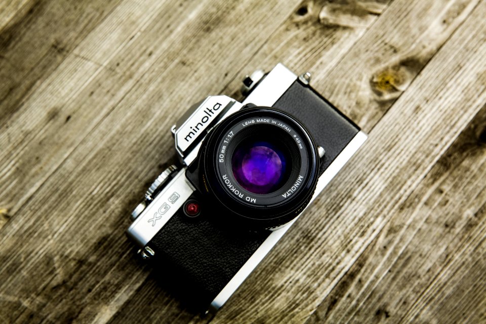 Black And Gray Minolta Dslr Camera On Top Of Brown Wooden Surface