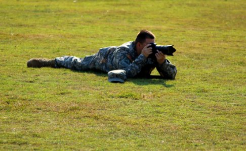 Military Crouching On Green Grass Using Dslr Camera During Daytime photo