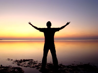 Silhouette Of Man Standing Beside Ocean During Sunset photo