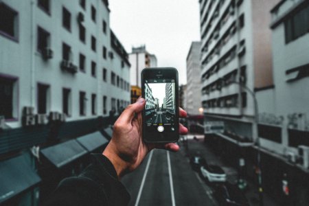 Man Holding Smartphone Capturing Roadway photo