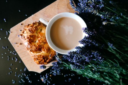 White Ceramic Mug With Brown Liquid Inside Beside Purple Flower And Pastry photo