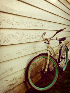 White And Teal Beach Cruiser Bike Beside White Painted Wooden Wall photo