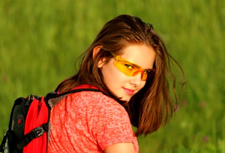 Woman In Red Shirt Wearing Backpack Surrounded By Green Grass Field photo