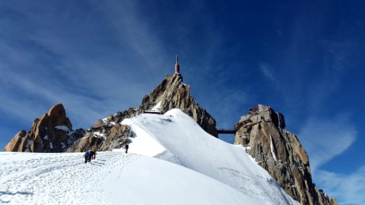 People Walking Toward Top Of Mountain On Snow Covered Ground During Daytime photo