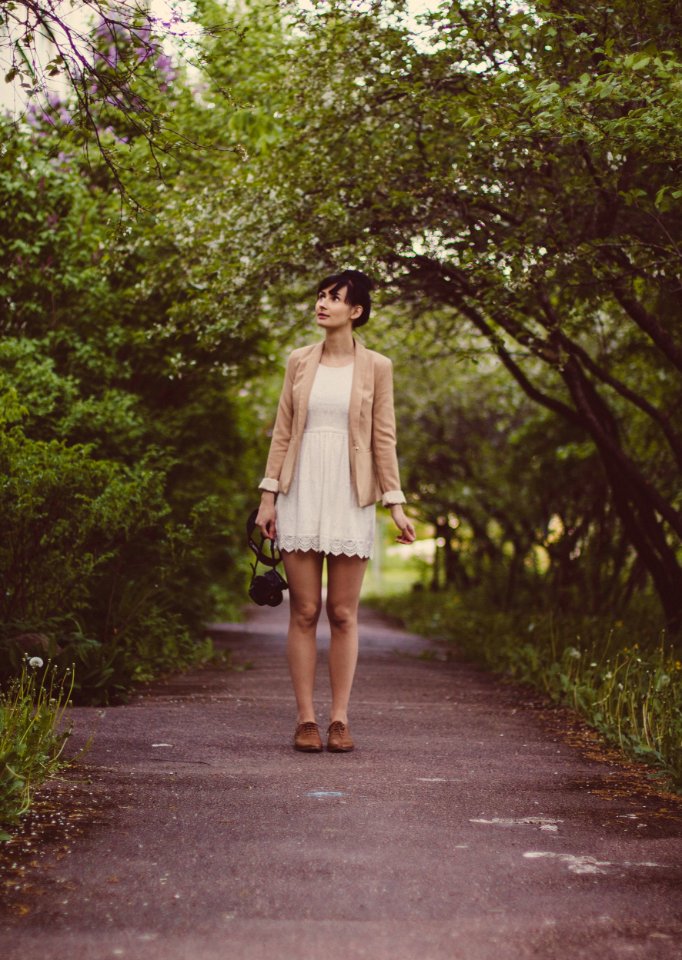 Woman In Beige Blazer Standing On Pathway Surrounded By Green Trees During Daytime photo