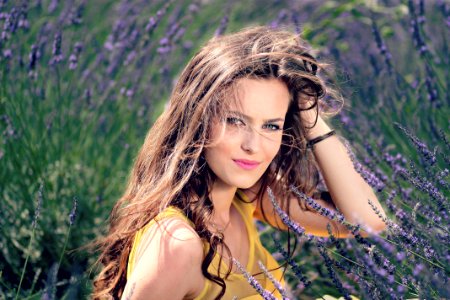 Womens Yellow Tank Top Holding Her Brown Curly Hair While Sitting On A Purple Flower
