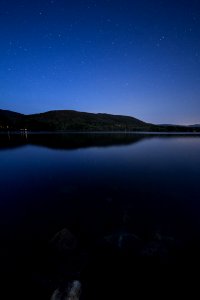 Lake View Under Clear Blue Night Sky During Night Time photo