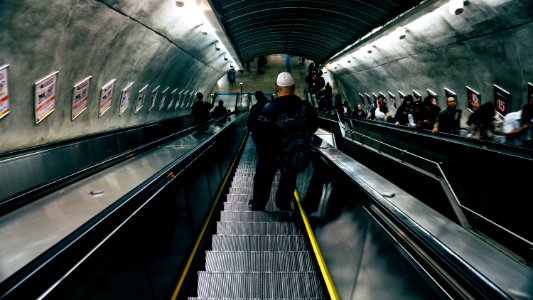 Man In Black Leather Jacket On Escalator photo