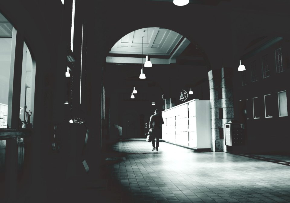 Silhouette Of A Person Walking On A Grey Floor Tiles Beside White Cabinet In Dark Room photo