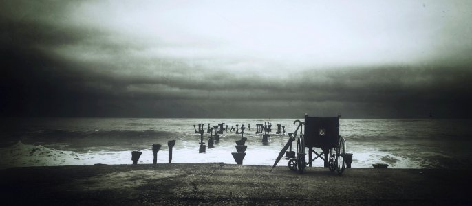 Grey Scale Photograph Of Wheel Chair Near Water Sea photo