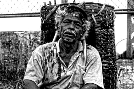 Man In Polo Shirt Sitting Near Brown Woven Basket Black And White Photography photo