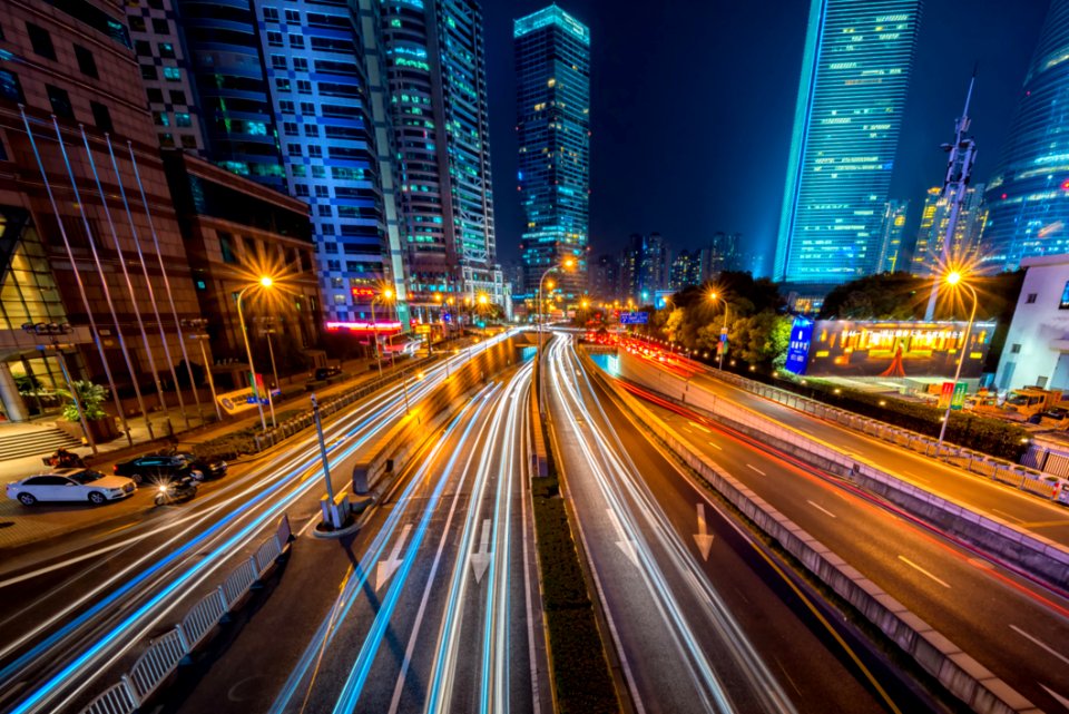 Timelapse Photography Of Vehicle On Concrete Road Near In High Rise Building During Nighttime