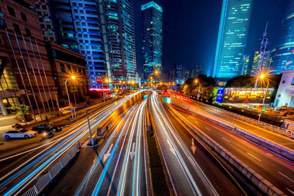 Timelapse Photography Of Vehicle On Concrete Road Near In High Rise Building During Nighttime photo