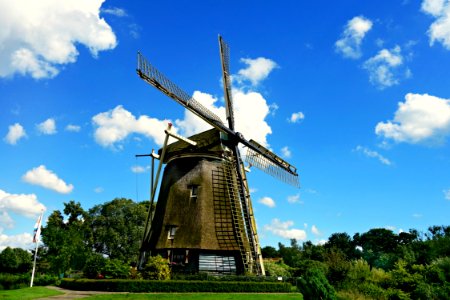 Brown And Black Windmill Under Cumulus Clouds Surrounded By Green Leaf Trees photo