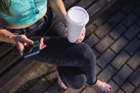 Woman Holding White Disposable Cup And Smartphone photo