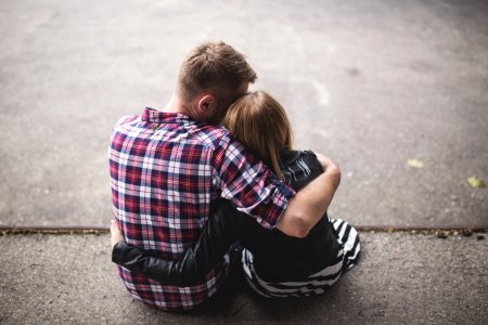 Man In Red White And Blue Check Long Sleeve Shirt Beside Woman In Black And White Stripes Shirt Hugging Each Other While Sitting O photo