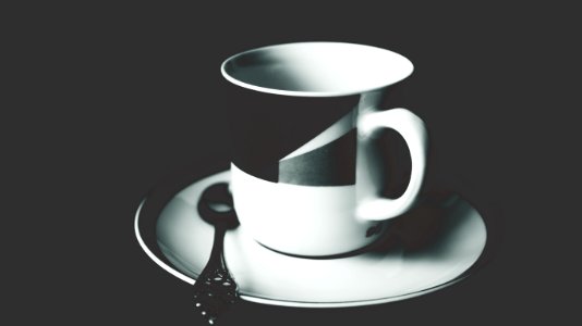 White And Black Ceramic Tea Mug On White Ceramic Round Plate And Stainless Steel Spoon On Top photo