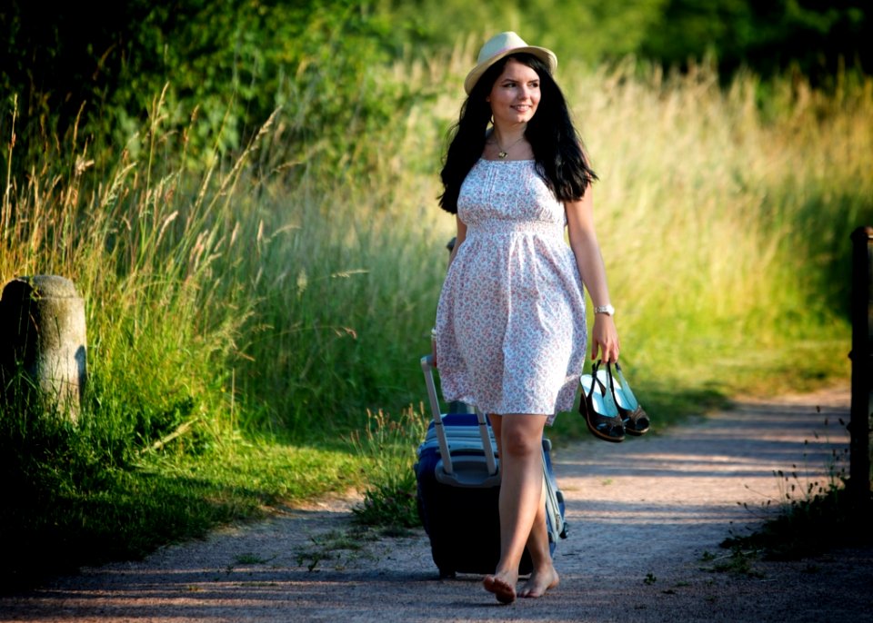Woman Walking While Carrying Shoes And Luggage Bag During Daytime