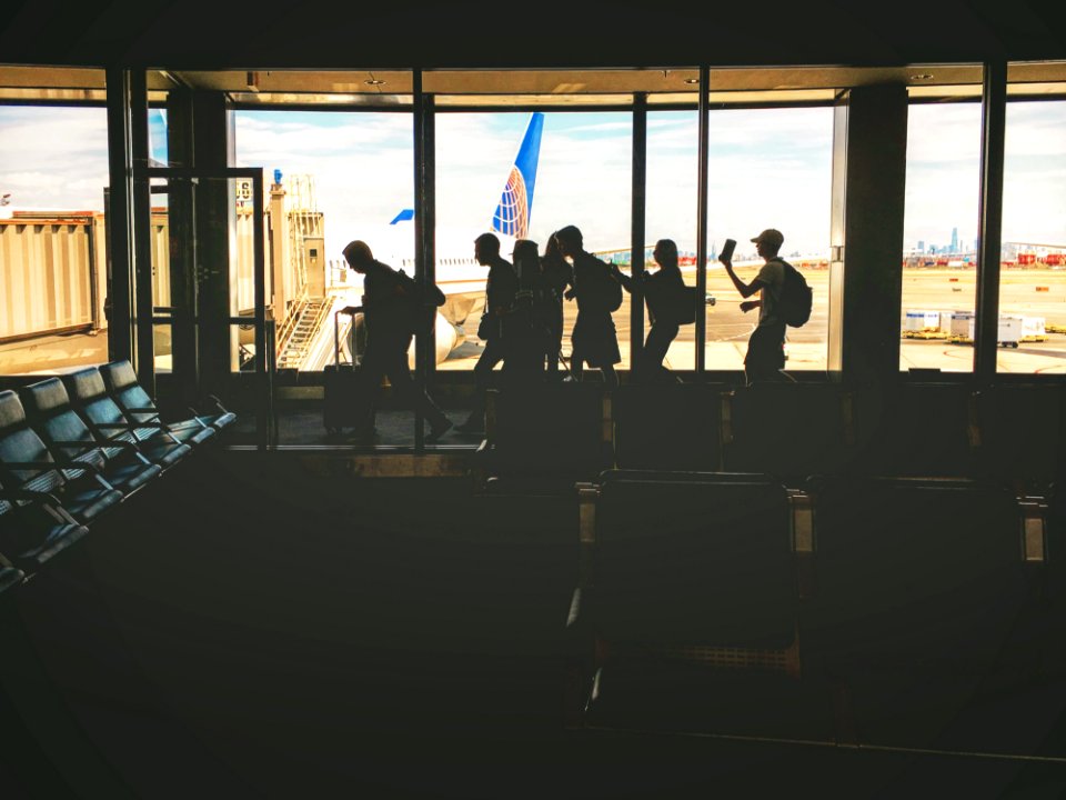 Group Of People Walking Near Clear Glass Window With A View Of White Airplane Parked During Daytime