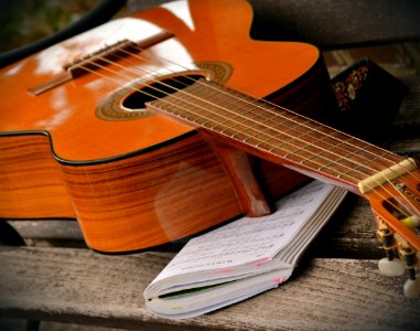 Brown Acoustic Guitar On White Music Note Book photo