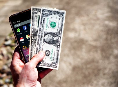 Persom Holding Black Android Smartphone And 2 1 Us Dollar photo