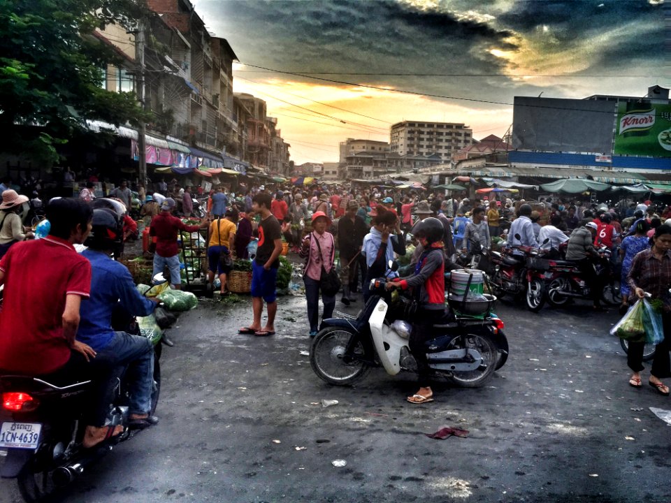 Woman In Gray And Red Jacket Riding White Motor In Crowded Place