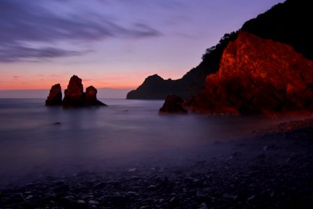 Tall Rock Formation Submerged In Water Near The Shore During Golden Hour photo