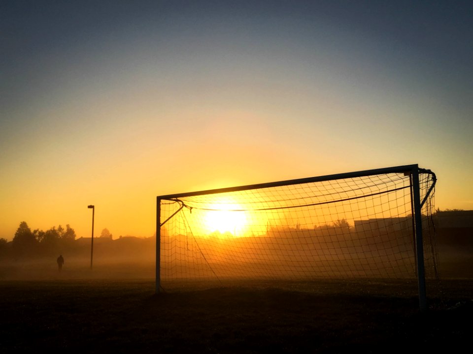 Person Jogging Near Soccer Goal During Sunrise