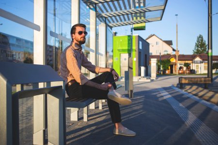 Man Wearing Sunglasses Sitting At Bus Stop During Daytime photo