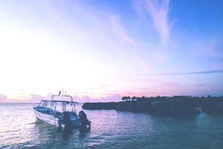 Boat Off Coastline At Sunset