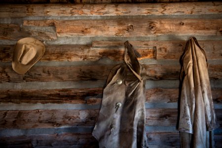 Coats and a cowboy hat at the "Hole-in-the-Wall" Cabin at Old Trail Town, a historic museum complex in Cody, Wyoming. Hole-in-the-Wall is a remote pass in the Big Horn Mountains of Johnson County, Wyoming. In the late 19th century the Hole in the Wall Gang, a group of cattle rustlers and other outlaws that included Butch Cassidy's Wild Bunch gang met at this cabin, built in 1883 and now preserved at the Old Trail Town museum. Original image from Carol M. Highsmith’s America, Library of Congress collection.