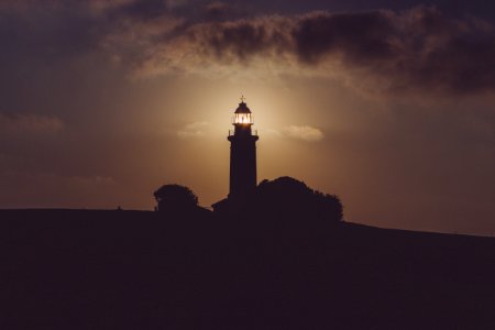 Silhouette Of Light House Under Gray Dark Sky photo