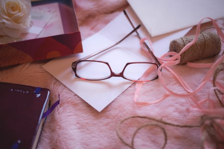 Eyeglasses Beside Pink Yarn On Pink Bed Blanket photo