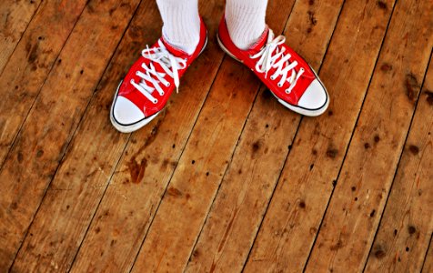 Person In Red Low Tops In Brown Wooden Floor photo