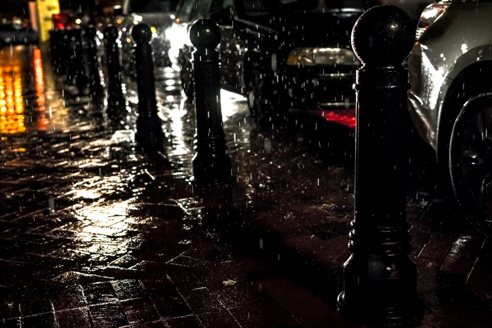 Black Posts On Black Pavement Beneath Falling Rain