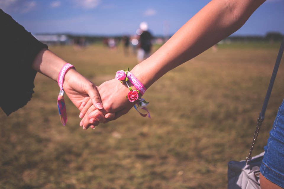 2 Person Holding Each Other Wearing Pink Friendship Bracelet During Daytime