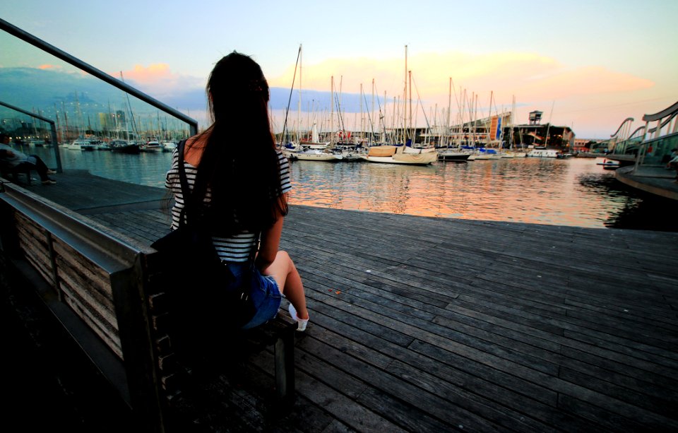 Woman In Black And White Stripe Scoop Neck Shirt Sitting On Brown Wooden Bench In Ship Dock During Daytime photo