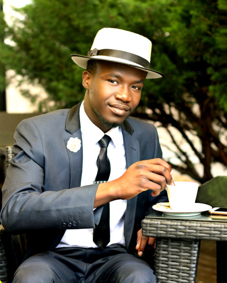 Man In Gray Formal Suit Jacket Stirring Coffee During Daytime