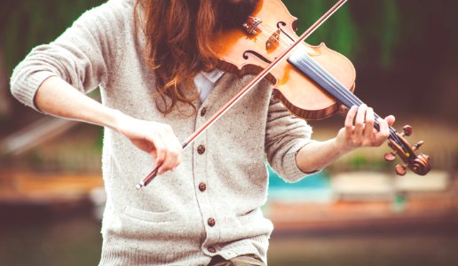 Woman In Gray Cardigan Playing A Violin During Daytime photo