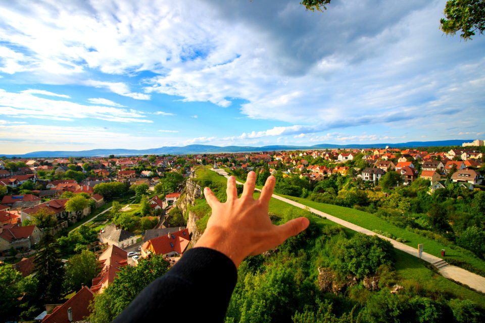 Human Hand Under White And Blue Sky On Green Grass Field