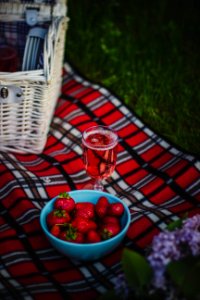 Clear Wine Glass With Wine Near Strawberry Fruit On Red White And Black Plaid Textile photo