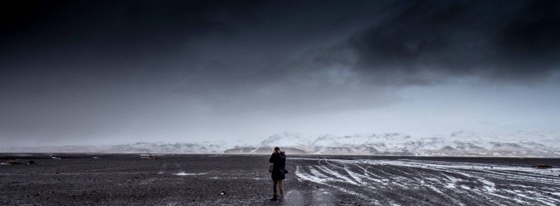 Man Standing On Gray Dessert Under Gray Cloudy Sky During Daytime photo