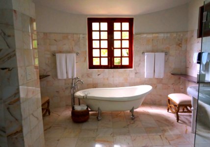 White Bathtub On White Tile Bathroom Near Brown Framed Clear Glass Window photo