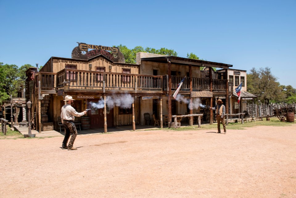 Two "gunslingers" (historical intrepreters Wes Hughes, left, and Thornton Young) fire away in a showdown on the street at the Enchanted Springs Ranch and Old West theme park, special-events venue, and frequent movie and television-commercial set in Boerne, Texas, northwest of San Antonio. Original image from Carol M. Highsmith’s America, Library of Congress collection.