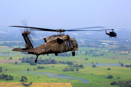 Brown Helicopter Flying Above Green Field During Daytime