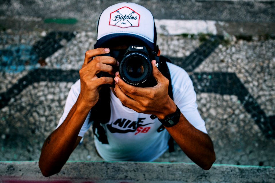 Man Wearing White Nike Sb Shirt Holding Black Dslr Camera
