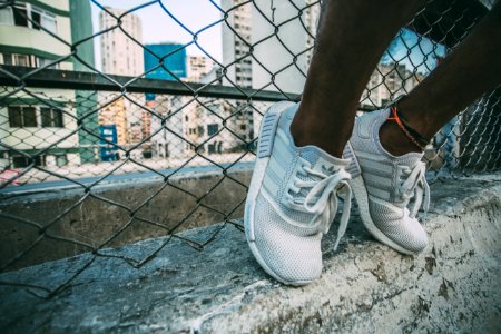 Person Wearing White Adidas Low Top Shoe Near Gray Cyclone Fence photo